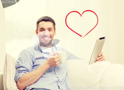 Image of smiling man working with tablet pc at home