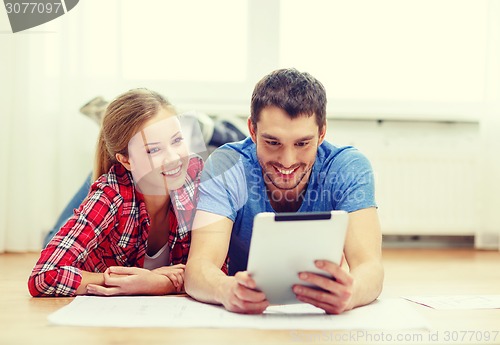 Image of smiling couple looking at tablet pc at home