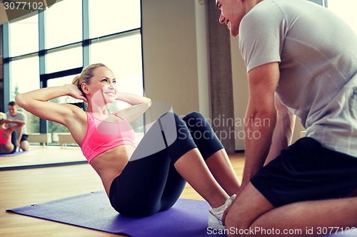 Image of woman with personal trainer doing sit ups in gym