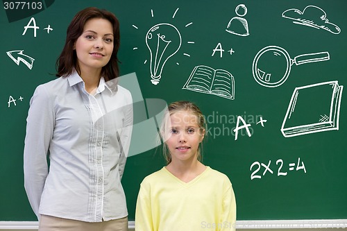 Image of little school girl with teacher at blackboard