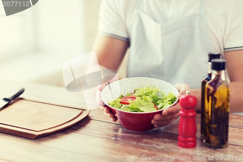 Image of close of male hand holding a bowl with salad