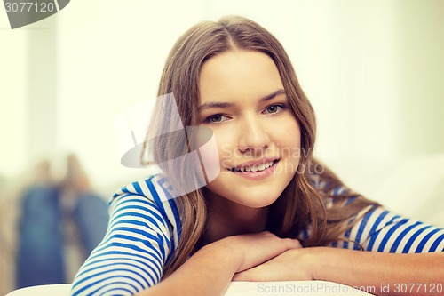 Image of smiling teenage girl lying on sofa at home