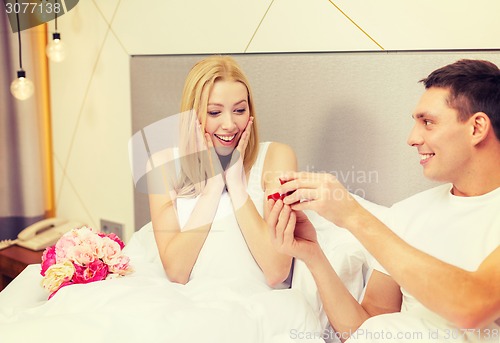 Image of man giving woman little red box and ring in it