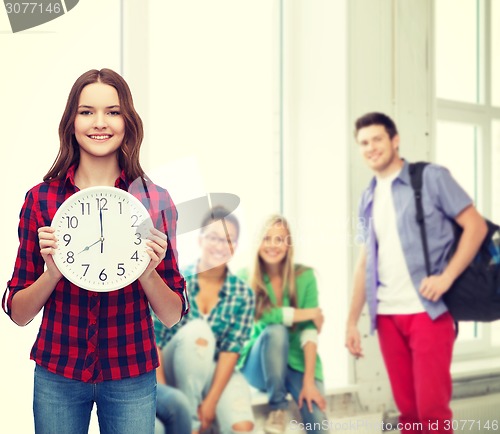 Image of young woman in casual clothes with wall clock