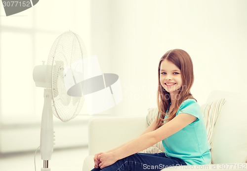 Image of smiling little girl with big fan at home