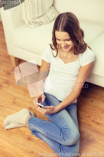 Image of smiling teenage girl with smartphone at home