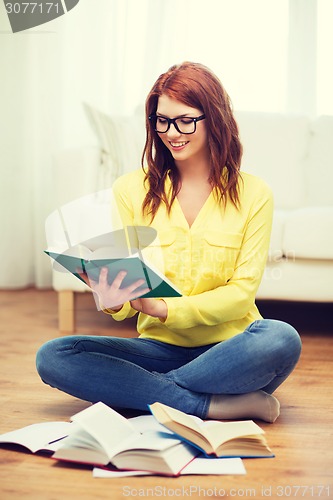 Image of smiling student girl reading books at home