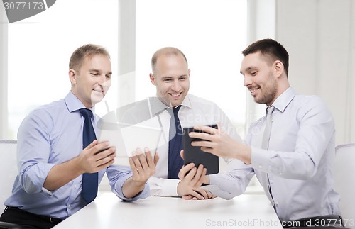 Image of three smiling businessmen with tablet pc in office