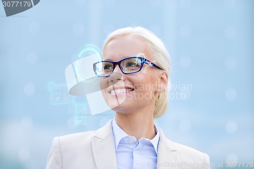 Image of young smiling businesswoman in eyeglasses outdoors