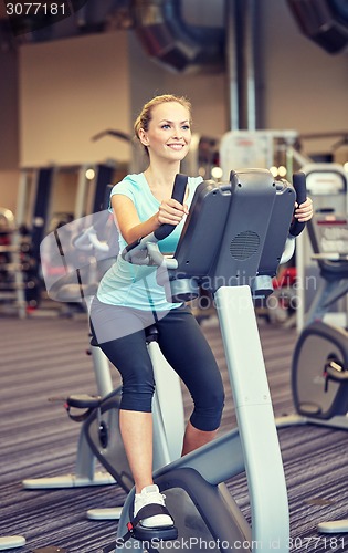 Image of smiling woman exercising on exercise bike in gym