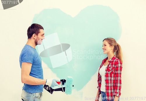 Image of smiling couple painting big heart on wall