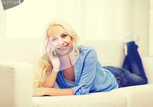 Image of smiling woman with smartphone at home