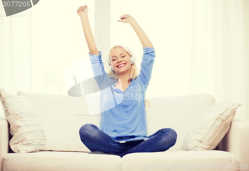 Image of woman with tablet pc and headphones at home