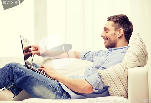 Image of smiling man working with laptop at home