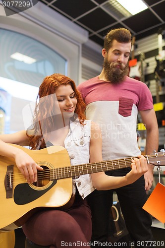 Image of couple of musicians with guitar at music store