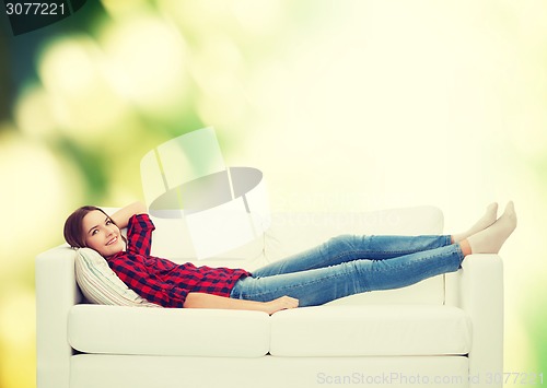 Image of smiling teenage girl lying on sofa