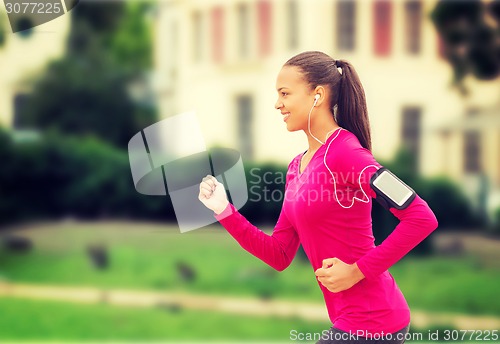 Image of smiling young woman running outdoors