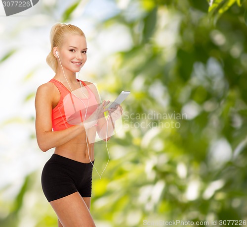 Image of smiling sporty woman with smartphone and earphones