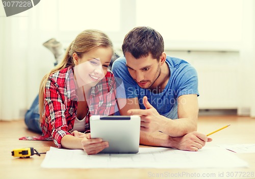 Image of smiling couple looking at tablet pc at home