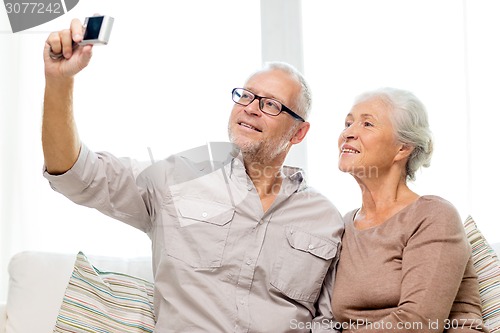 Image of happy senior couple with camera at home