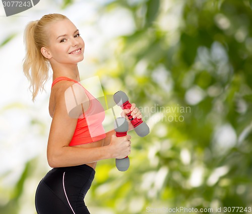 Image of smiling beautiful sporty woman with dumbbells