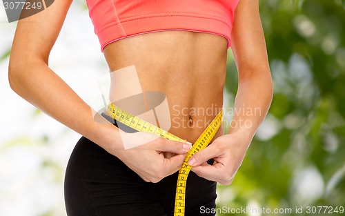 Image of close up of female hands measuring waist