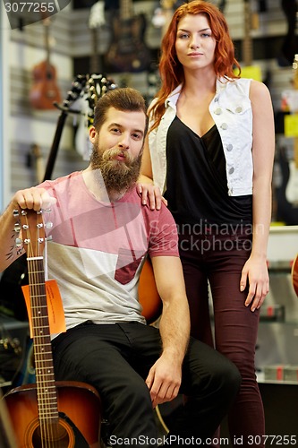 Image of couple of musicians with guitar at music store