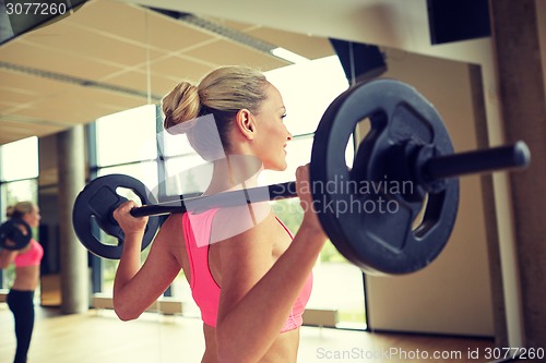 Image of sporty woman exercising with barbell in gym