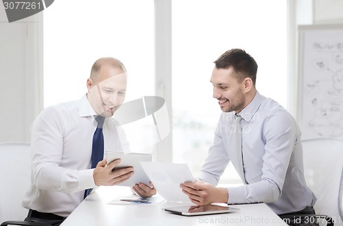 Image of two smiling businessmen with tablet pc in office