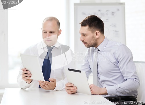 Image of two serious businessmen with tablet pc in office