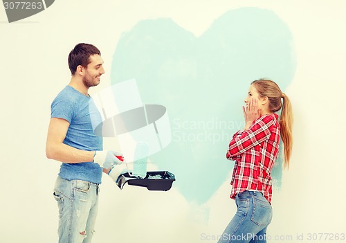 Image of smiling couple painting big heart on wall