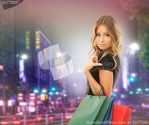 Image of young happy woman with shopping bags over city