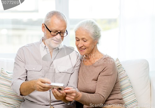 Image of happy senior couple with camera at home