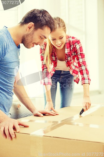 Image of smiling couple opening big cardboard box