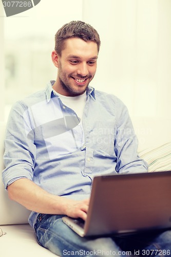 Image of smiling man working with laptop at home