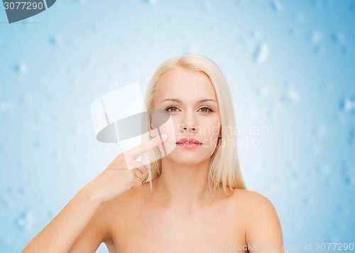 Image of calm young woman pointing at her cheek