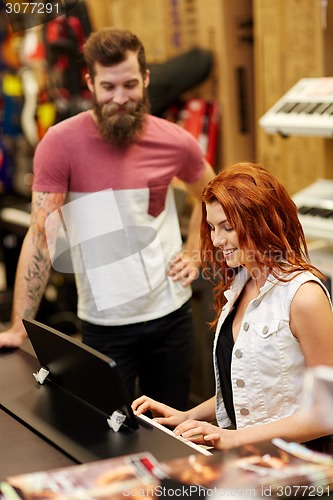 Image of man and woman playing piano at music store