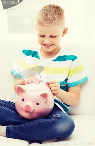 Image of smiling little boy with piggy bank and money