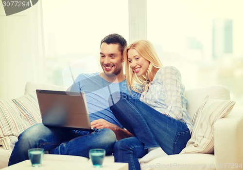 Image of smiling happy couple with laptop at home