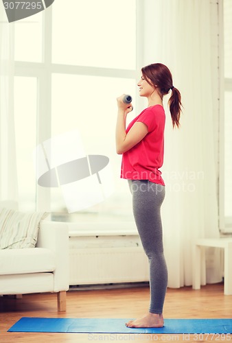 Image of smiling teenage girl exercising with dumbbells