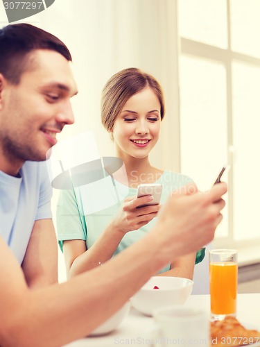 Image of smiling couple with smartphones reading news