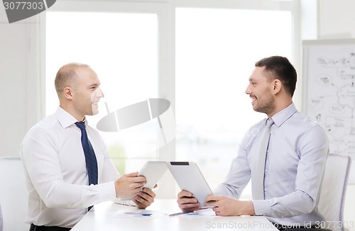 Image of two smiling businessmen with tablet pc in office