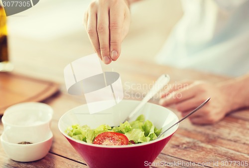 Image of close up of male hands flavouring salad in a bowl