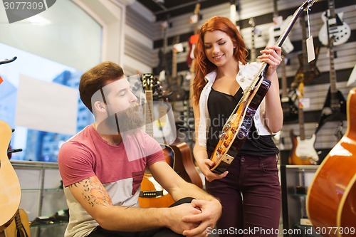 Image of couple of musicians with guitar at music store