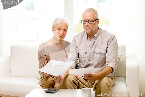 Image of senior couple with papers and calculator at home