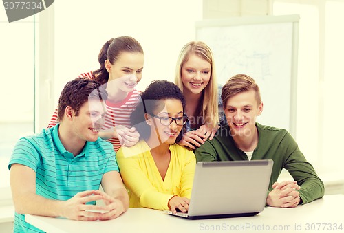 Image of smiling students looking at laptop at school