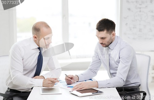 Image of two serious businessmen with tablet pc in office