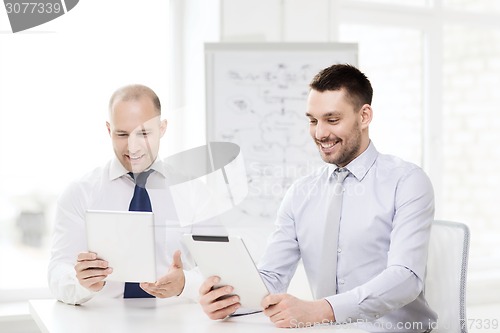 Image of two smiling businessmen with tablet pc in office