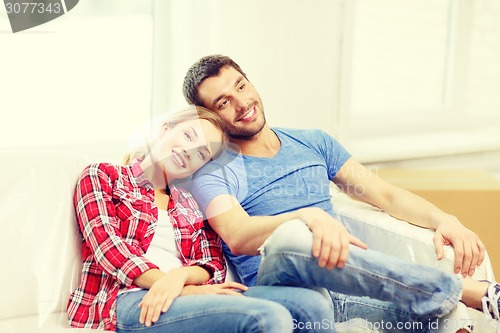 Image of smiling couple relaxing on sofa in new home