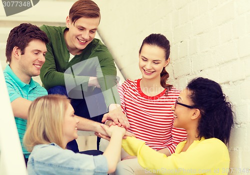 Image of smiling students with hands on top of each other